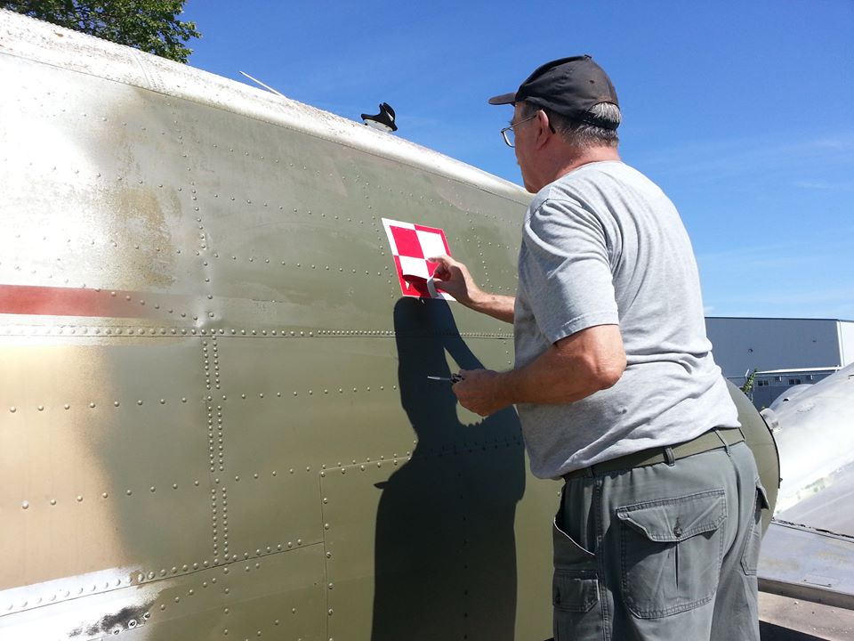 A volunteer places the red and white insignia of the Polish air force on the fuselage of the “Spirit of Ostra Brama”, a C-47 (DC-3) Dakota flown by Polish airmen serving with the Royal Air Force during the Second World War. The aircraft is being repatriated to Poland from 17 Wing Winnipeg, Manitoba. PHOTO: Submitted